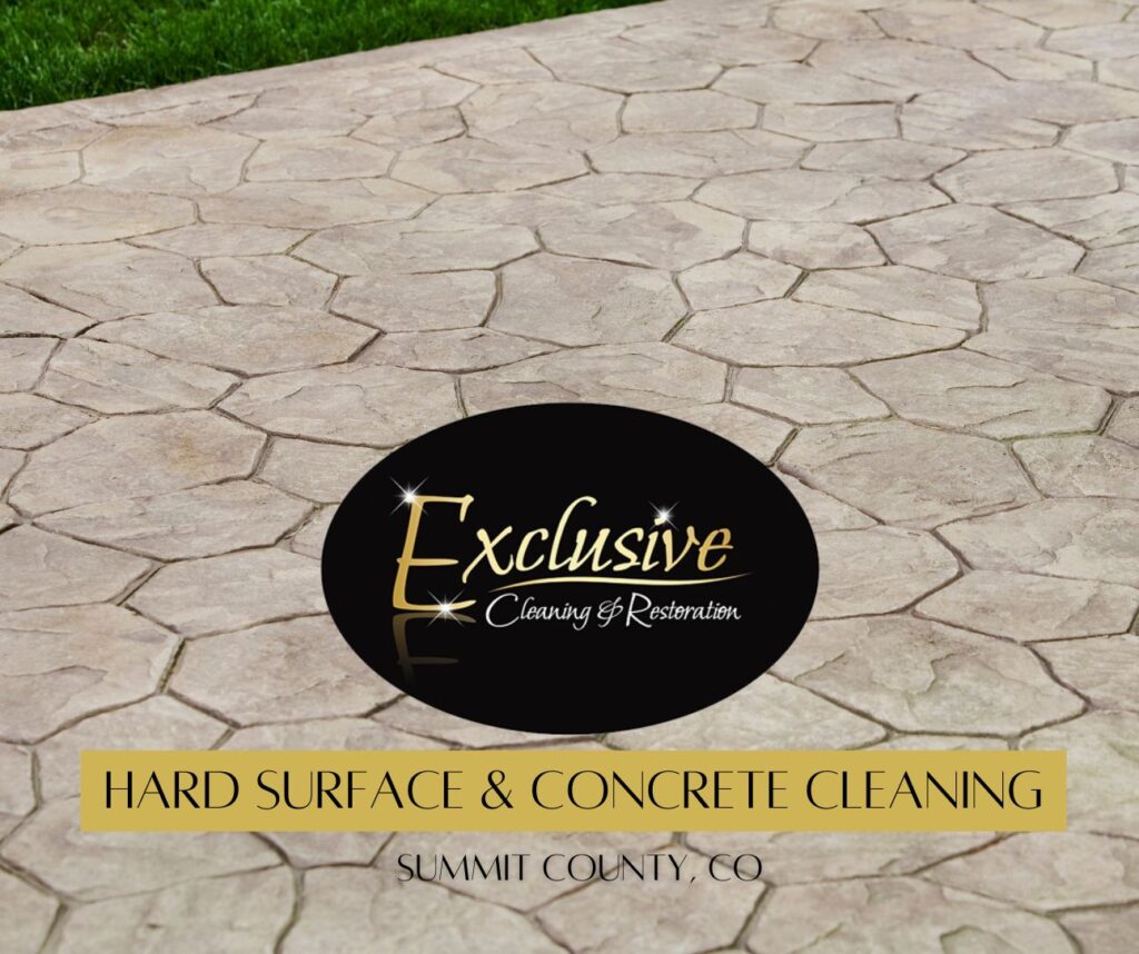 An outdoor concrete area with a patch of grass in the corner. The ahrd surface/ concrete looks professionally cleaned